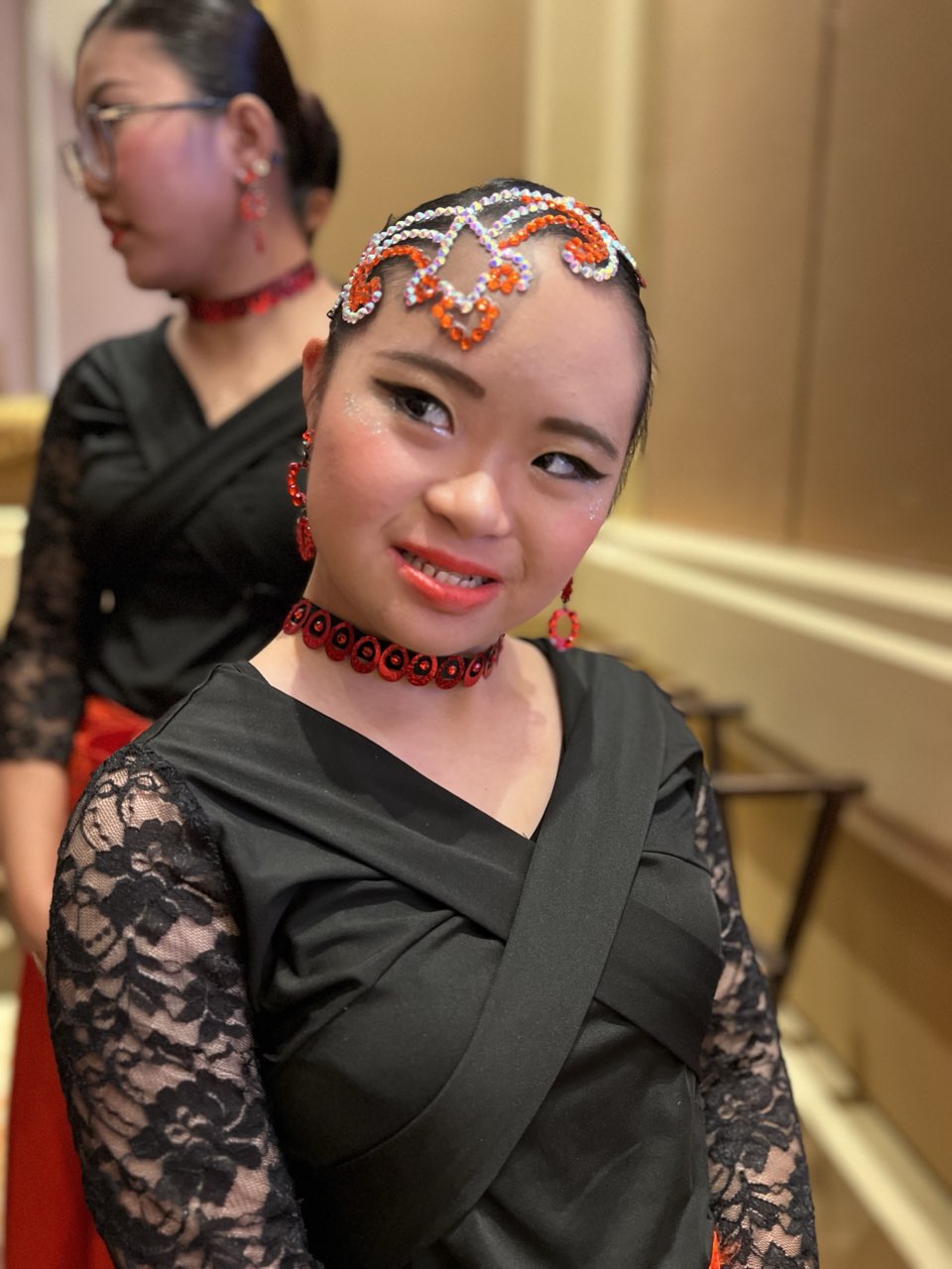 Megan Tang backstage in a black lace costume with a beaded headpiece and red choker